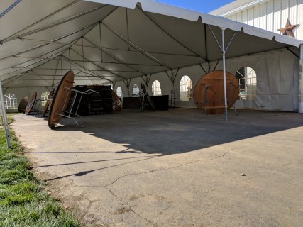 Wedding Reception - 30' x 75' Frame Tent (Free Span) on Driveway, Cathedral Sidewalls, Wood Chairs, Round Tables, Rectangular Head Tables. Anchored on One Side with Water Barrels.